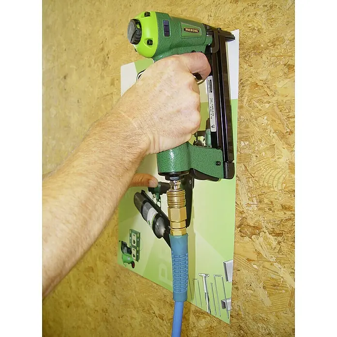 Prebena Druckluftnagler 1XR-A16 - Betriebsdruck: 4 bar - 7 bar, Passend für: Prebena Heftklammern der Type A von 4 - 16 mm - Nahaufnahme eines grünen Druckluftnaglers mit blauem Schlauch vor einer Wand.