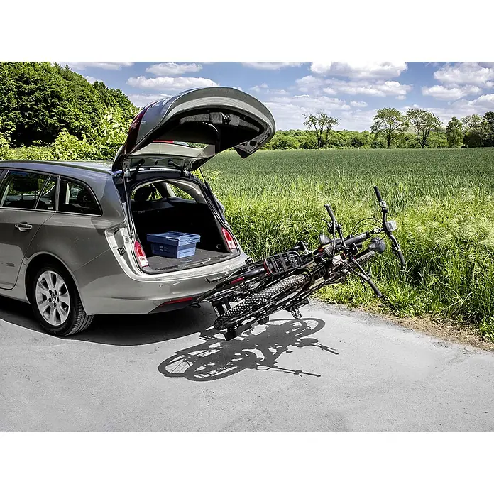 Eufab Fahrradträger Finch - Geeignet für: 2 Fahrräder/E-Bikes, Traglast: 60 kg - Silberner Kombi mit geöffneter Heckklappe und einem montierten Fahrradträger mit zwei Fahrrädern. Eine blaue Kiste steht im Kofferraum.