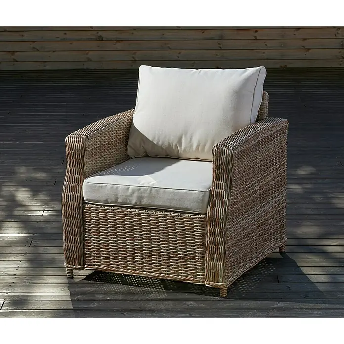 Sillón de exterior Gotland - An x Pr x Al: 80 x 81 x 77 cm, Aluminio/Ratán sintético, Beige - Un cómodo sillón de ratán con cojines claros colocado en una terraza de madera, perfecto para relajarse al aire libre.