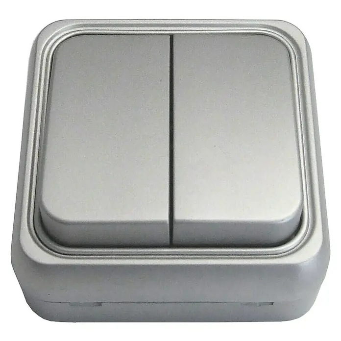 Fontini BF-18 Interruptor/Conmutador doble - Aluminio, Plástico, Colocar - Primer plano de un interruptor de luz doble plateado con bordes redondeados, montado en una superficie blanca.