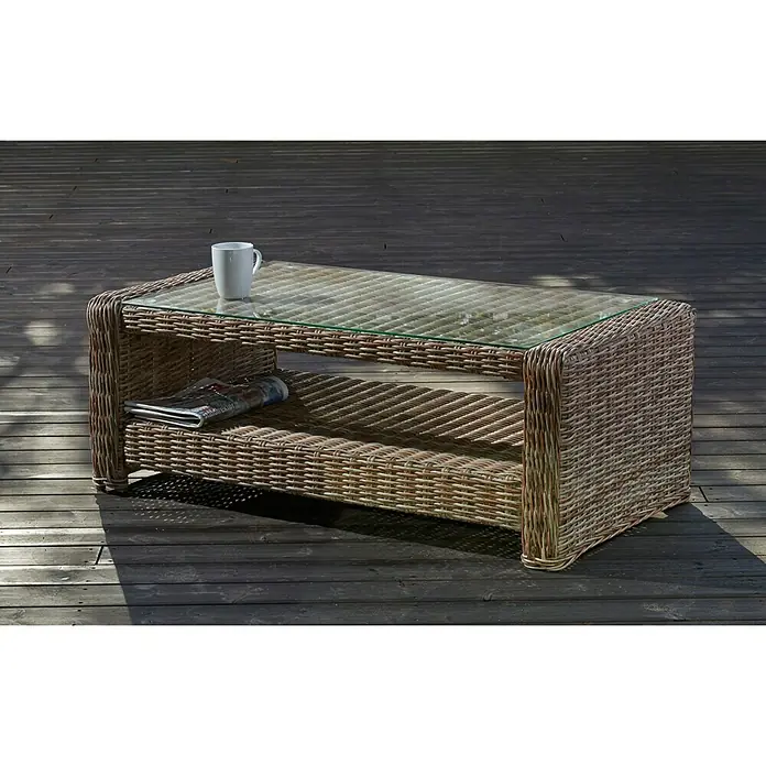 Mesa auxiliar de jardín Gotland - L x An x Al: 111 x 56 x 41 cm, Beige - Una mesa de ratán con tapa de vidrio y espacio de almacenamiento, decorada con una taza y periódico. Perfecta para exteriores.