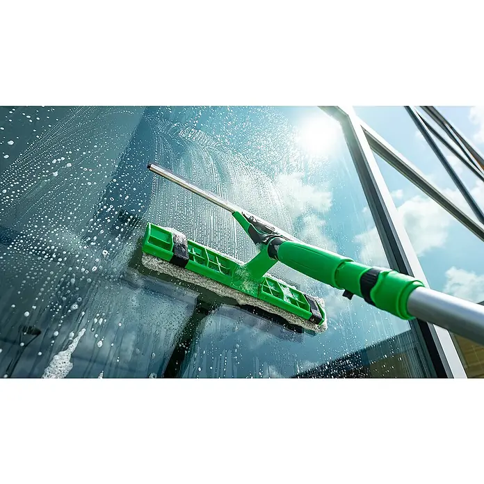 Unger Mikrofaser-Reinigungspad Visa Versa Pro - Breite Bezug: 35 cm, 100 % Polyacryl (Fasern) - Bild einer Fensterreinigungsbürste mit Teleskopstiel, die eine Glasscheibe mit Seifenlauge reinigt und für streifenfreie Sauberkeit sorgt.