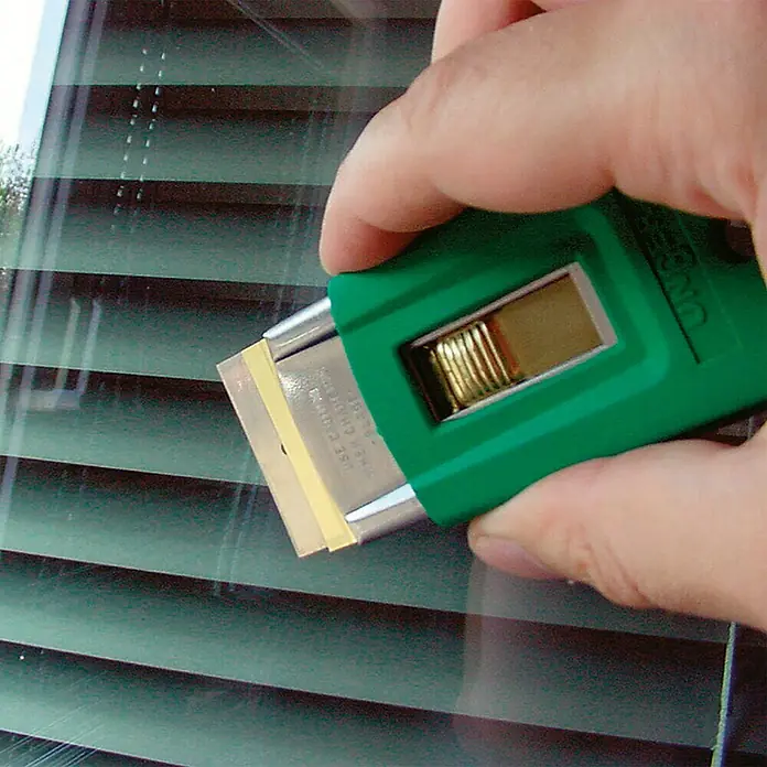 Unger ErgoTec Glasreinigungs-Set - 11 -tlg. - Das Bild zeigt einen UNGER Glasschaber in Grün mit einer scharfen Klinge zum Entfernen von hartnäckigen Verschmutzungen auf Glasoberflächen.
