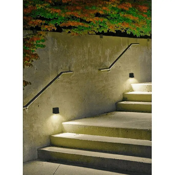 Forlight Aplique exterior LED Loyd - 4,1 W, 6,2 x 7,9 x 14 cm, Antracita, IP55, 2 ud. - Una imagen atmosférica de una escalera exterior con barandillas, iluminada por luces de pared que emiten un cálido resplandor. El follaje añade color.