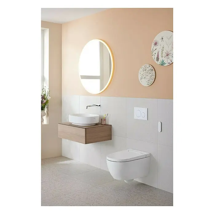 Geberit Wand-Dusch-WC-Set AquaClean Alba - Spülrandlos, Ohne Spezialglasur, Spülform: Tief, WC Abgang: Waagerecht, Weiß - Modernes Badezimmer mit hängendem WC, Waschtisch mit Aufsatzwaschbecken, rundem Spiegel und Wandfliesen in hellen Farben.