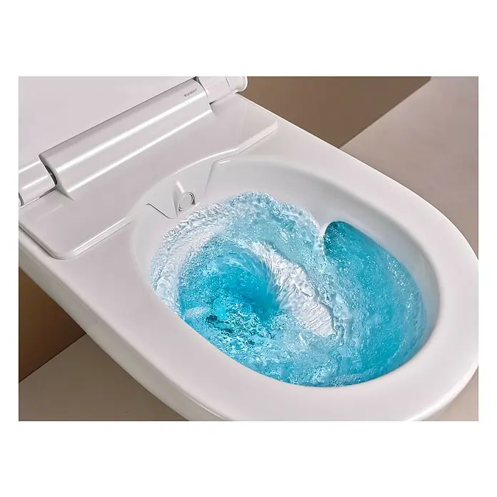 Geberit Wand-Dusch-WC-Set AquaClean Alba - Spülrandlos, Ohne Spezialglasur, Spülform: Tief, WC Abgang: Waagerecht, Weiß - Nahaufnahme einer Geberit AquaClean Toilette mit blauem Wasser, das die innovative Spültechnologie hervorhebt.