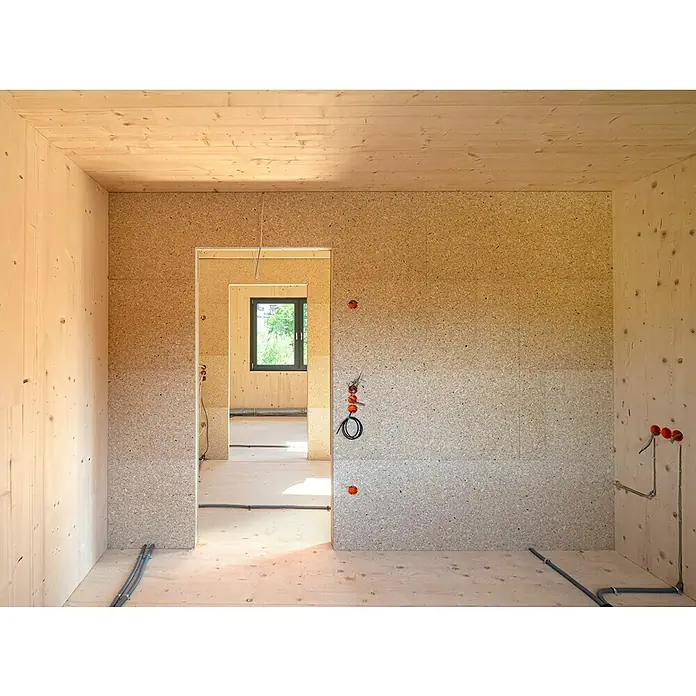elka ESB-Platte Plus - 2.580 x 675 x 15 mm, Geschliffen - Unfertiger Raum mit Holzverkleidung, Rohinstallationen für Strom und Wasser. Natürliches Licht fällt durch das Fenster.