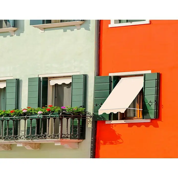 SmartSun Toldo ventana Essential - Crudo, Ancho: 1,2 m, Caída: 1,2 m - Fachada colorida con ventana, persianas verdes y un toldo. Un toque de color en la arquitectura que llama inmediatamente la atención.