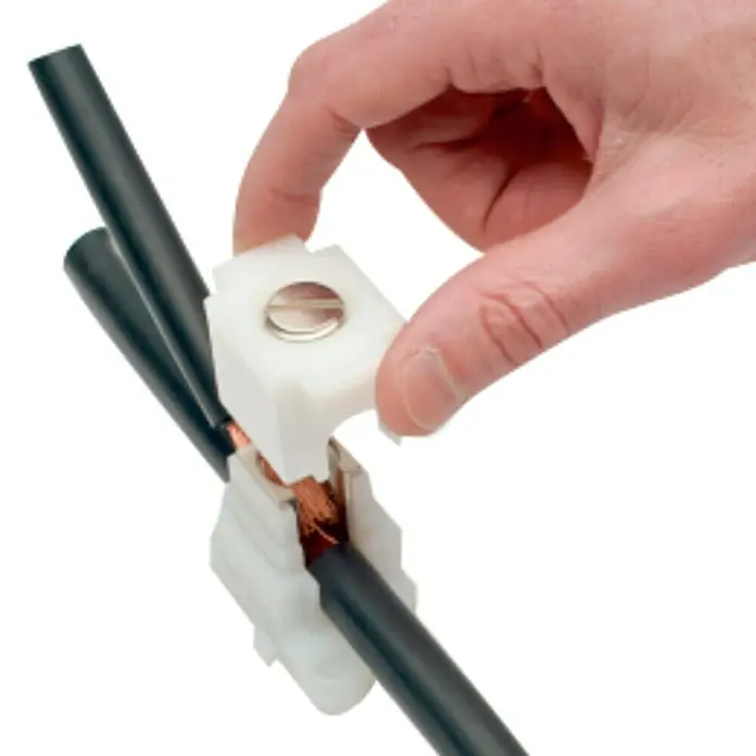 Regleta de bornes HPS35 - L x An x Al: 36 x 36 x 34 mm, Número de polos: 12 ud., Latón - La imagen muestra un primer plano de un conector de empalme de cables que se adjunta a un cable, con una mano sujetando el conector.