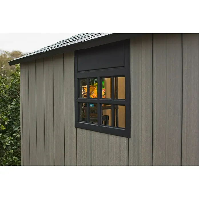 Keter Gartenhaus - Außenmaß inkl. Dachüberstand (B x T): 229 x 223,5 cm, Anthrazit/Grau, Kunststoff, Grundfläche: 4,5 m² - Nahaufnahme eines Gartenhauses mit Fenster. Das Fenster hat schwarze Rahmen und gibt den Blick ins Innere des Hauses frei.