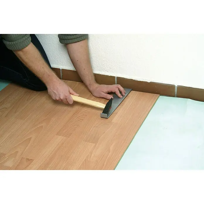Wolfcraft Zugeisen - 310 x 25 x 15 mm, Metall - Bild eines Handwerkers, der Laminat mit einem Hammer und Zugeisen verlegt, um eine feste und präzise Passform zu gewährleisten.