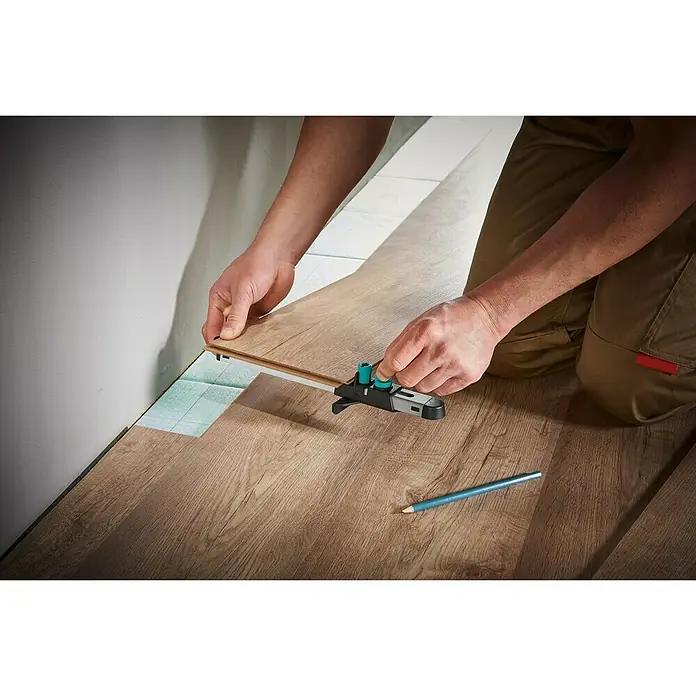 Wolfcraft Anreißlehre - Länge: 295 mm - Eine Person, die ein Wolfcraft-Produkt zum Verlegen eines Laminatbodens verwendet, wobei ein Bleistift bereitliegt.
