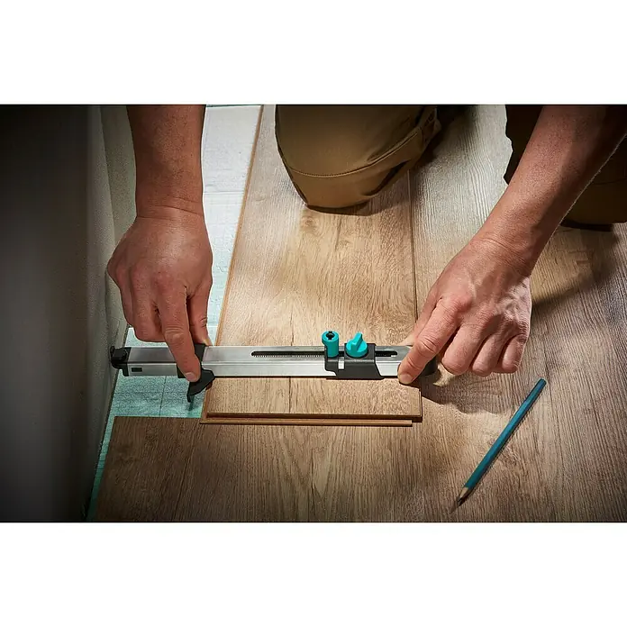 Wolfcraft Calibrador - Largo: 295 mm, Plástico - Un hombre utiliza un medidor de contornos Wolfcraft para marcar una forma en un suelo laminado para un ajuste perfecto.