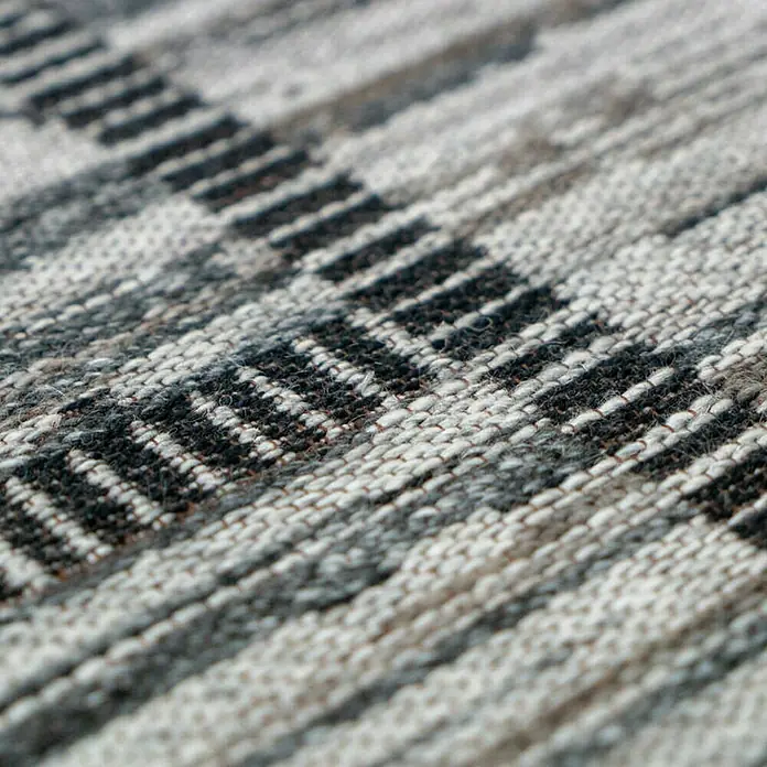 Kayoom Flachgewebeteppich Phönix - Natur/Grau, 150 x 80 cm, 75 % Wolle, 20 % Baumwolle, 5 % Polyester - Nahaufnahme eines Teppichs mit einem Muster aus grauen und schwarzen Streifen.