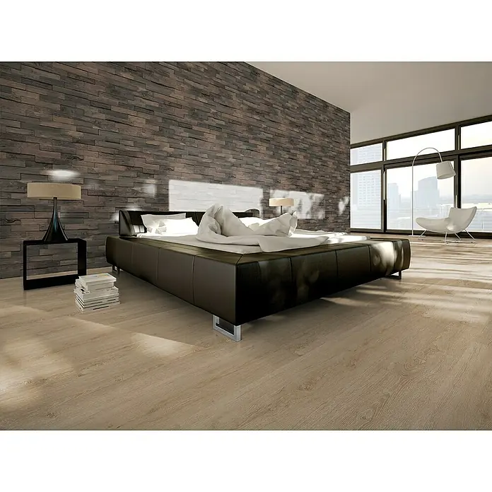 Indo Wandpaneel 3D Wall Driftwood Bali Sea - Hevea, 560 x 200 x 10 mm, 1,008 m² - Elegantes Schlafzimmer mit einem großen, schwarzen Bett, das auf einem hellen Holzboden steht. Die Ziegelwand verleiht dem Raum eine rustikale Note.