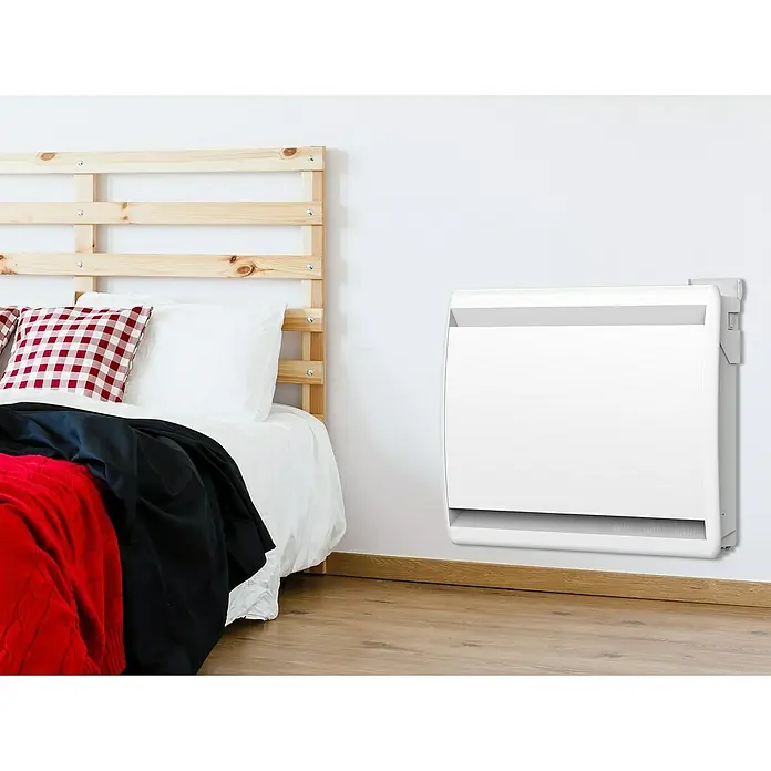 Purline Emisor térmico Micairon A1500 WiFi - 1.500 W, Blanco, 10 x 75 x 55 cm - Un radiador de convección blanco montado en la pared en un dormitorio con suelos de madera y una cama al fondo. Proporciona calor para la habitación.