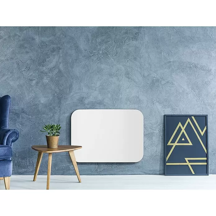 Purline Emisor térmico Ceramic AC1000 WiFi - 1.000 W, Blanco, 10 x 73 x 53 cm - Un panel rectangular blanco de esquinas redondeadas en una pared azul texturizada, sobre una mesa pequeña con una planta.