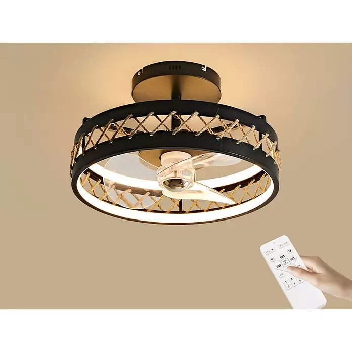Purline Ventilador de techo Ceily Rope - Negro, 50 cm, 52 W, Blanco cálido - Ventilador de techo negro con luz LED integrada y celosía decorativa de cuerda, montado en el techo. Una mano sostiene un control remoto blanco.