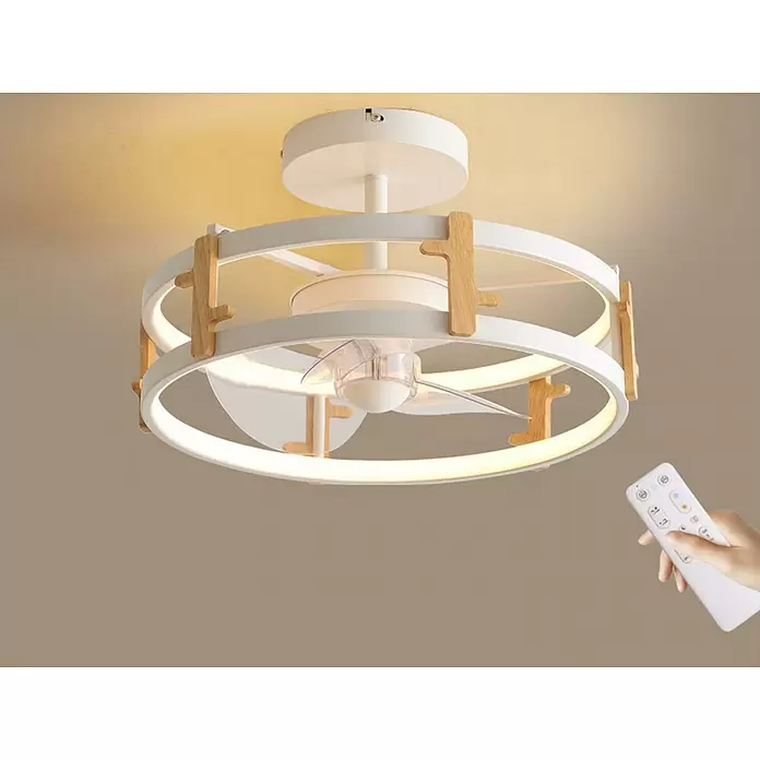 Purline Ventilador de techo Ceily Wood - Blanco, 40 cm, 42 W, Blanco cálido - Ventilador de techo blanco moderno con luz, integrado en dos marcos circulares con detalles de madera clara, controlado por un mando a distancia blanco en la mano.