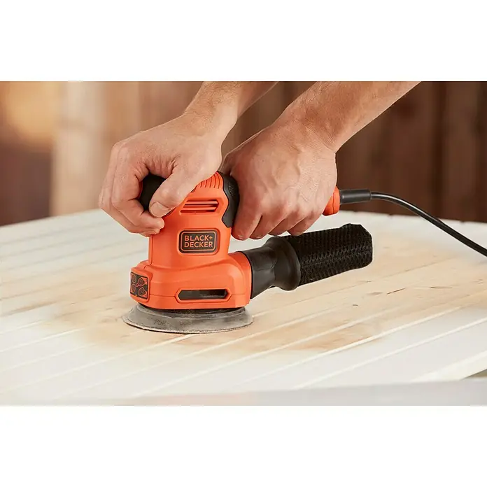 Black+Decker Lijadora multifunción eléctrica  BEW200-QS - 200 W, Número de oscilaciones marcha en vacío: 12.000 r.p.m., Diámetro circuito oscilante: 2 mm - Un primer plano de una lijadora orbital Black+Decker que se utiliza sobre una superficie de madera.