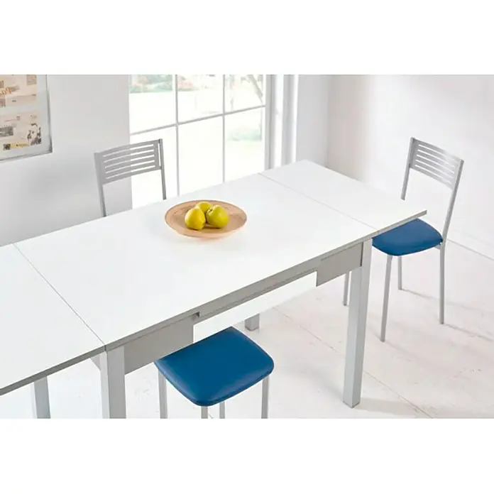 Mesa Meri - L x An: 110 x 70 cm, Material del tablero de la mesa: MDF, Blanco - Una mesa de comedor extensible con tableros blancos y patas gris plateado, rodeada de sillas a juego con asientos azules.