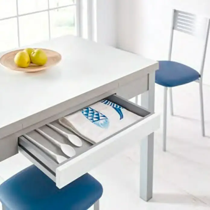 Mesa Meri - L x An: 110 x 70 cm, Material del tablero de la mesa: MDF, Blanco - Mesa con cajón extraíble con cucharas y un paño de cocina con estampado de peces, con manzanas en un bol sobre la mesa.