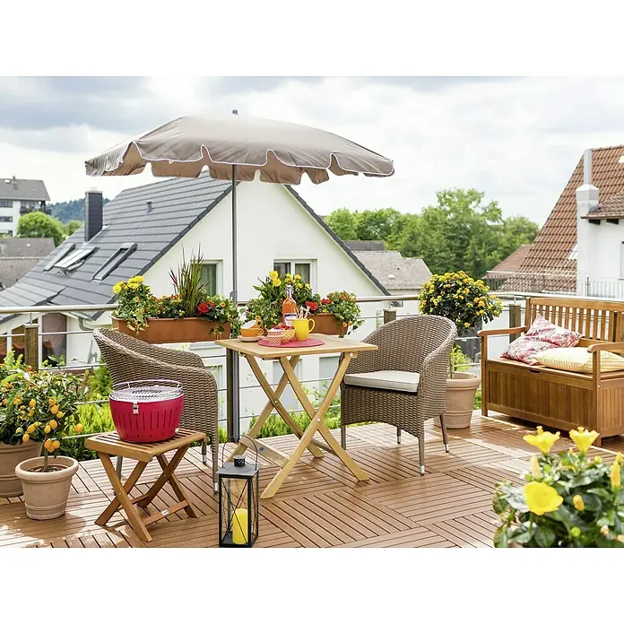Sunfun Balkonschirm Messina II - Taupe, Bespannungsmaß (L x B): 180 x 120 cm - Aufnahme eines Terrassensets mit Tisch, Stühlen, Sonnenschirm und Grill, umgeben von üppigen Pflanzen und farbenfrohen Blumenarrangements.