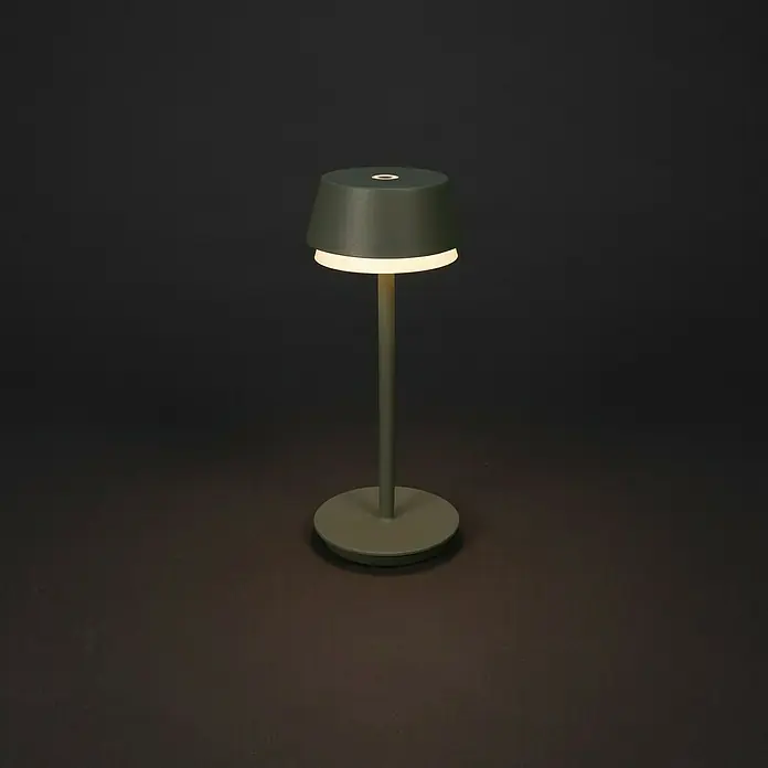 Konstsmide Akku-Tischleuchte Lyon - 2,5 W, L x B x H: 12 x 12 x 30 cm, Mintgrün, RGBW - Nahaufnahme einer stilvollen grünen Tischleuchte, die ein warmes, sanftes Licht in einem dunklen Raum spendet.