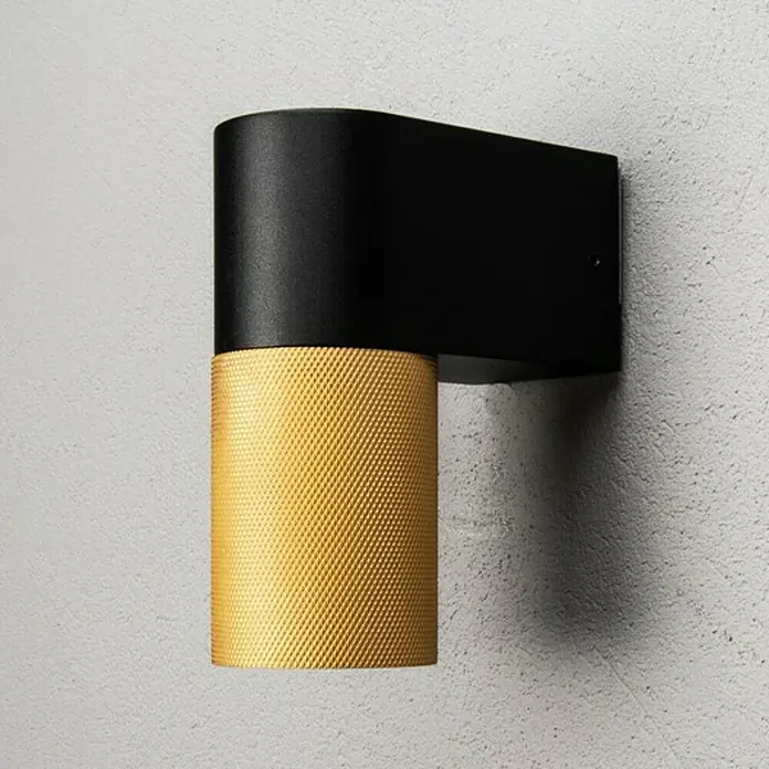 Konstsmide Außenwandleuchte Temi - 7 W, Schwarz/Gold, IP54 - Elegante Wandleuchte mit einem schwarzen, abgerundeten Gehäuse und einem goldenen, zylinderförmigen Schirm mit strukturierter Oberfläche.