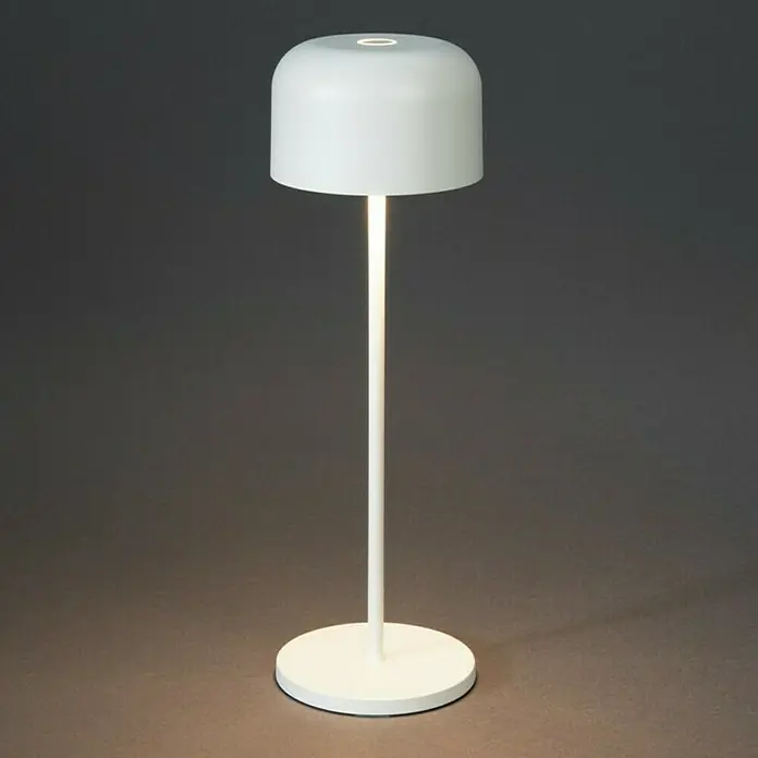 Konstsmide Akku-Tischleuchte Lille - 3,5 W, L x B x H: 11 x 11 x 36 cm, Weiß, Mehrfarbig - Nahaufnahme einer modernen, weißen Tischleuchte mit einem runden Fuß und einem schlichten, zylindrischen Lampenschirm auf einem grauen Hintergrund.