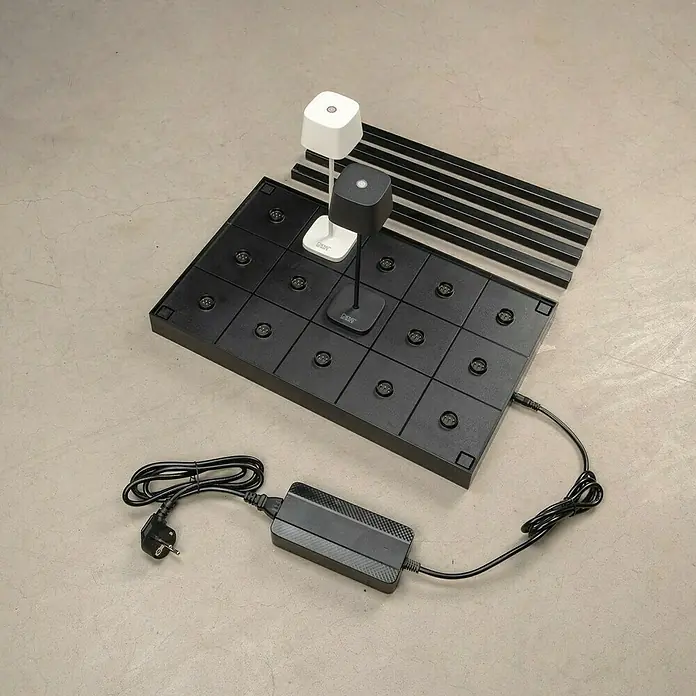 Konstsmide Ladestation für Mini-Tischleuchten - 15 Ladeplätze - Das Bild zeigt das Palmiye LED-Tischleuchten-System mit seinem Zubehör, einschließlich Netzteil und zusätzlichen Leisten, auf einem neutralen Hintergrund.
