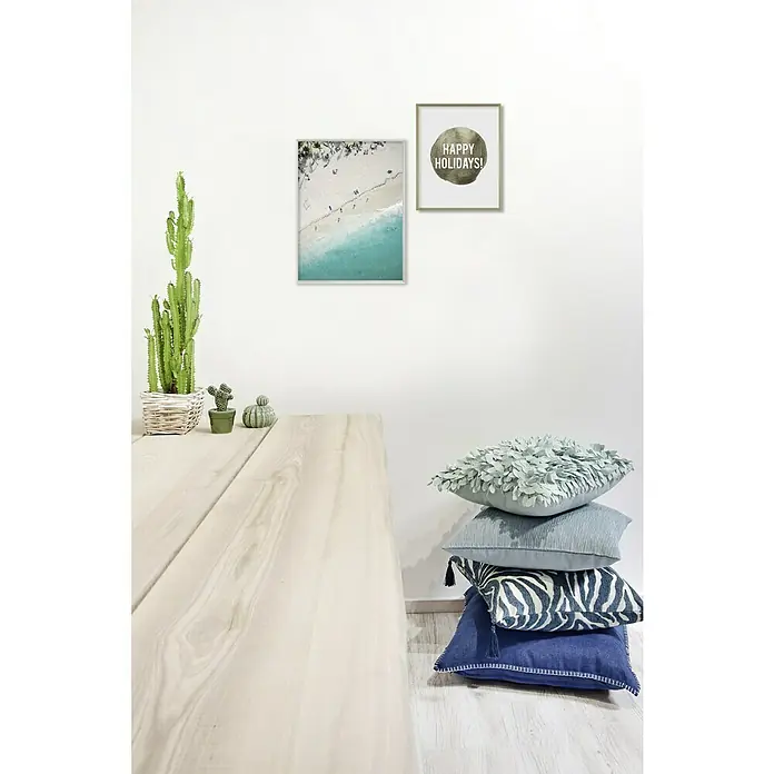 Nielsen Alurahmen Pixel - 50 x 50 cm, Schwarz - Einladende Szene mit Kissenstapel, hölzernem Tisch und gerahmten Bildern an einer weißen Wand, die eine gemütliche Raumatmosphäre erzeugen.