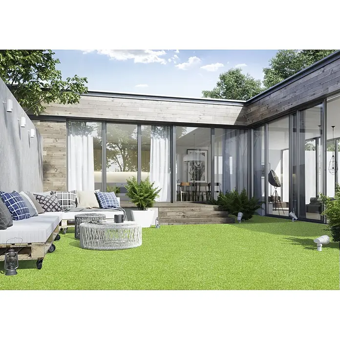 Kunstrasen Meterware Palma - Breite: 400 cm, Grün, Mit Drainagenoppen - Eine Terrasse mit Kunstrasen. Der Rasen ist üppig und grün und erstreckt sich über die gesamte Fläche. Im Hintergrund befindet sich ein modernes Haus.