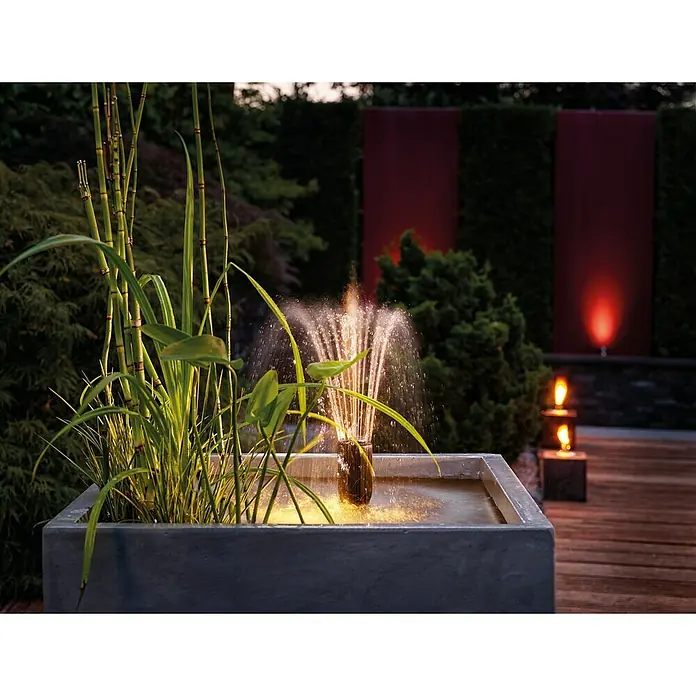 Oase Unterwasserfilter Filtral UVC 1500 - 5 W, Teichgröße: 1,5 m³ - Brunnen mit Wasserspiel und Pflanzen in einem rechteckigen Betonbecken. Im Hintergrund Garten mit Beleuchtung für eine stimmungsvolle Atmosphäre.