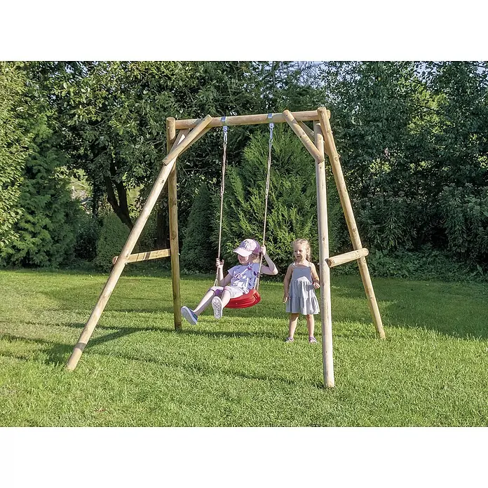 Joda Schaukel Poldi - B x L: 230 x 225 cm, Holz - Eine Kinderschaukel aus Holz im Garten mit einem Mädchen, das schaukelt, und einem Mädchen, das zuschaut. Das Schaukelset ist aus hellem Holz gefertigt.