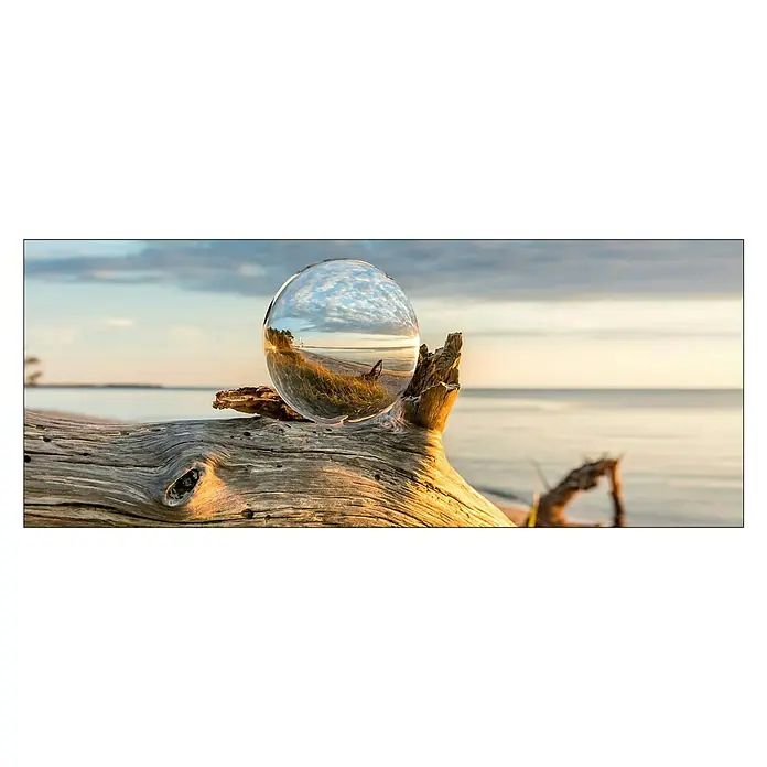 ProArt Glasbild - Drop on Wood, B x H: 80 x 30 cm - Glaskugel auf einem Holzstamm am Strand, die die Landschaft verzerrt und in einer neuen Perspektive zeigt. Die Kugel reflektiert das Licht.