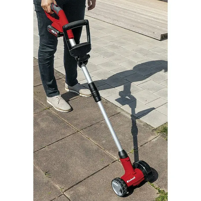 Einhell Power X-Change 18V Akku-Fugenreiniger GC-CC 18 Li-Solo - 18 V, Ohne Akku - Nahaufnahme eines Akku-Fugenkratzers von Einhell im Einsatz auf Pflastersteinen. Das Gerät ist rot und schwarz mit einem silbernen Griff.
