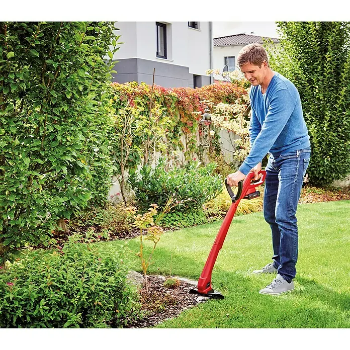 Einhell Power X-Change 18V Akku-Rasentrimmer GC-CT 18/24 Li P - 18 V, 1,5 Ah, Li-Ionen, 1 Akku - Ein Mann benutzt einen roten Einhell Akku-Rasentrimmer im Garten, um die Rasenkanten zu pflegen. Das Gerät ist handlich und effizient.