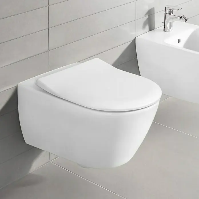 Villeroy & Boch Subway 2.0 Wand-WC - Spülrandlos, Mit schmutzabweisender & antibakterieller Glasur, Spülform: Tief, WC Abgang: Waagerecht, Weiß - Nahaufnahme einer modernen, wandhängenden Toilette in Weiß mit einem Bidet im Hintergrund, ideal für stilvolle Badezimmerdesigns.