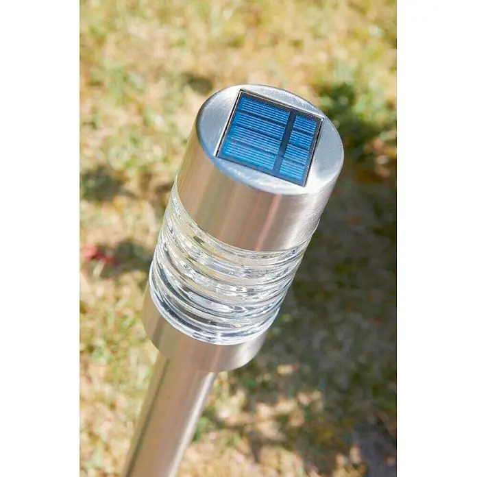 Luxform Solar-Erdspieß Torino - L x B x H: 7,5 x 7,5 x 58 cm, Silber, 8 lm - Nahaufnahme einer Solarleuchte aus Edelstahl mit einem geriffelten, transparenten Glasbereich, die auf einer Rasenfläche steht.