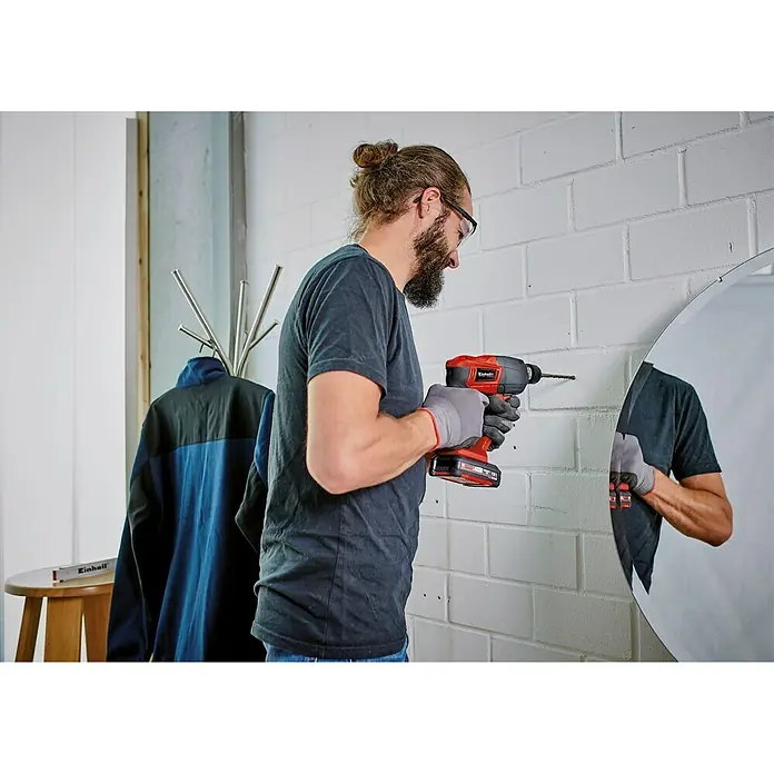 Einhell Power X-Change 18V Akku-Bohrhammer TE-HD 18 Li-Solo - 18 V, Ohne Akku - Ein Mann bohrt mit einem Einhell-Akkuschrauber ein Loch in eine Ziegelwand. Der Akkuschrauber ist rot und schwarz und hat einen Akku.