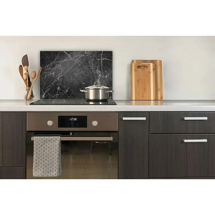 CUCINE Küchenrückwand - Black Marble, 60 x 40 cm, Stärke: 6 mm, Einscheibensicherheitsglas (ESG) - Detailaufnahme einer modernen Küche mit einem Herd, Holzlöffeln, Schneidebrettern und einem Spültuch, die eine stilvolle Küchenszene zeigen.