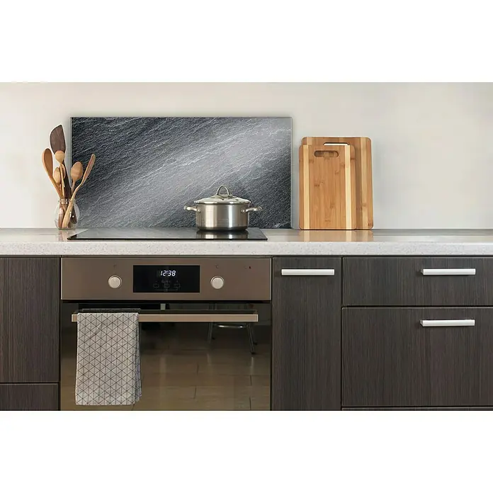 CUCINE Küchenrückwand - Schiefer, 80 x 40 cm, Stärke: 6 mm, Einscheibensicherheitsglas (ESG) - Küchenspüle mit Spülbecken, Herd und Holzbesteck. Der Fliesenspiegel hat eine grau melierte Steinoptik. Schneidebretter runden das Bild ab.