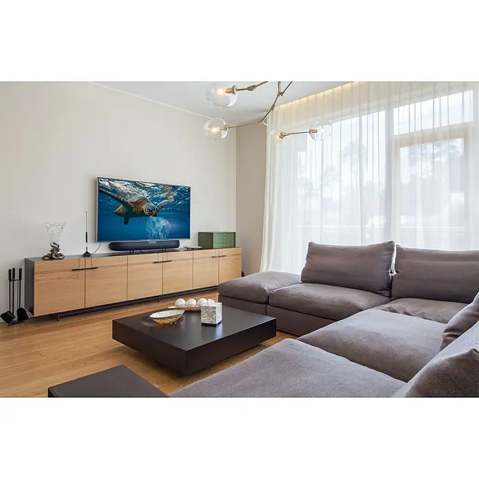 Hama Zimmerantenne Basic, passiv - DAB+, DAB, DVB-T2, UKW, Kabellänge: 1,45 m, Koax - Wohnzimmer mit einem modernen Lowboard aus Holz, auf dem ein grosser Fernseher steht, und einer grauen Couch.