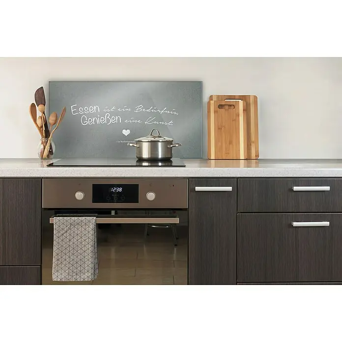 CUCINE Küchenrückwand - Essensgenuss, 80 x 40 cm, Stärke: 6 mm, Einscheibensicherheitsglas (ESG) - Das Bild zeigt eine moderne Küche mit einem stilvollen Herd, einem dekorativen Kochfeld-Spritzschutz und praktischen Schneidebrettern.