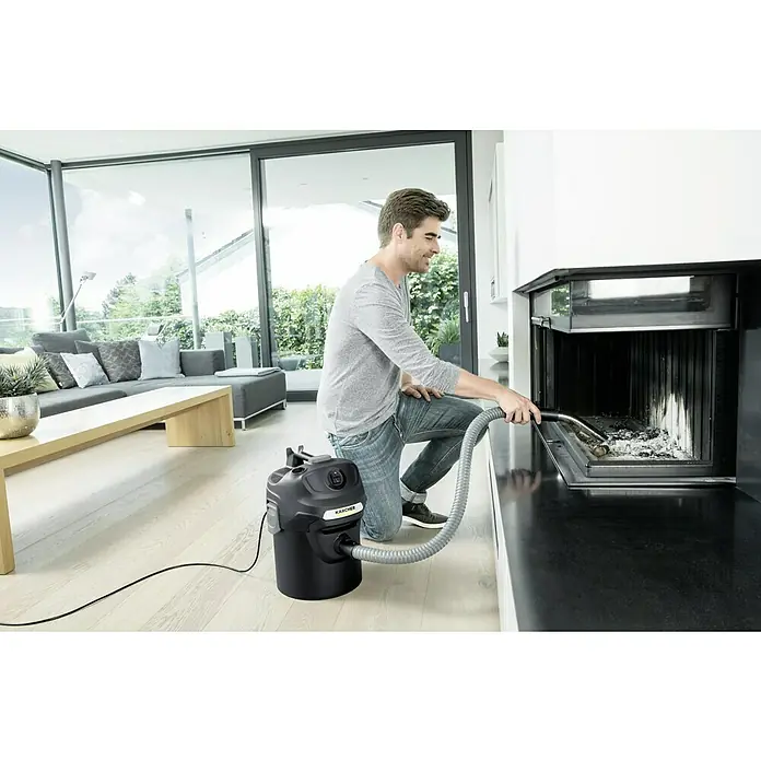 Kärcher Elektro-Aschesauger AD 2 - Leistungsaufnahme: 600 W - Ein Mann reinigt mit einem Kärcher Aschesauger einen Kamin. Der Sauger steht auf einem hellen Holzboden in einem modernen Wohnzimmer.