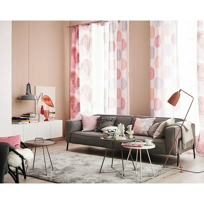 SCHÖNER WOHNEN-Farbe Farbtester TrendfarbeHortensie, Matt, 50 ml, Konservierungsmittelfrei - Ein graues Sofa mit Kissen in einem Wohnzimmer mit gemusterten Vorhängen, einem Teppich und Beistelltischen.