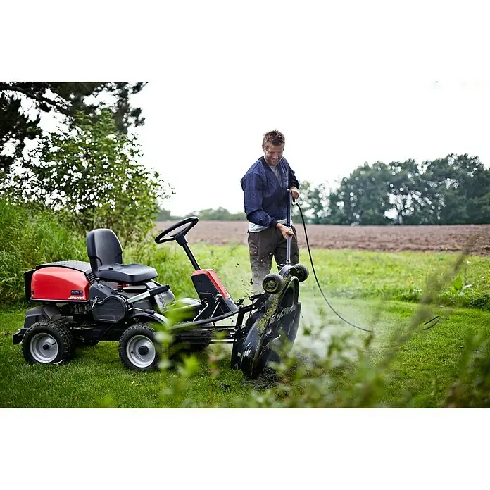 Nilfisk Hochdruckreiniger Premium 180-10 - 2.900 W, Max. Druck: 180 bar, Fördermenge: 610 l/h - Ein Mann reinigt einen roten Jonsered Aufsitzmäher im Freien mit einem Schlauch, um Grasreste zu entfernen.