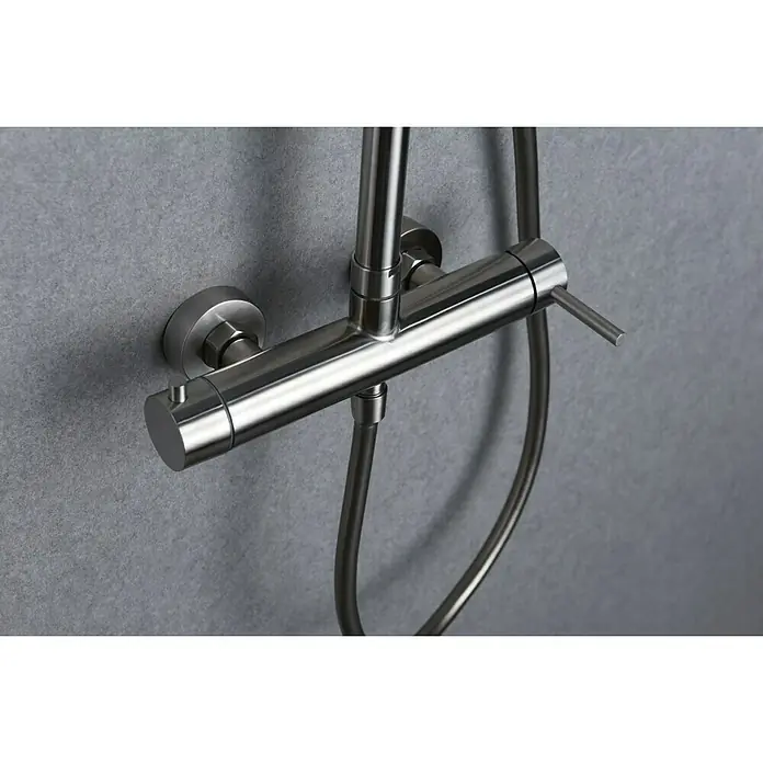 Imex Moscú Sistema de ducha - Con grifo monomando, Distancia entre orificios: 15 cm, Número de tipos de chorro: 1 ud., Cromo - Primer plano de un moderno grifo de ducha de acero inoxidable cepillado montado en una pared gris.