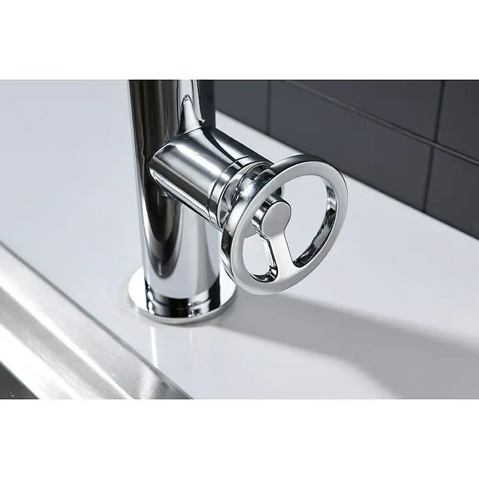 Imex Olimpo Grifo de cocina - Cromo, Resplandeciente - Primer plano de un grifo moderno y elegante con un mango de rueda sobre un lavabo blanco y limpio.